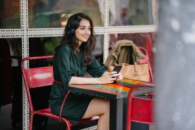 Genç Hintli Asyalı kadın o onun Smartphone-e doğru onun kulaklık streaming müzik hoşlanır