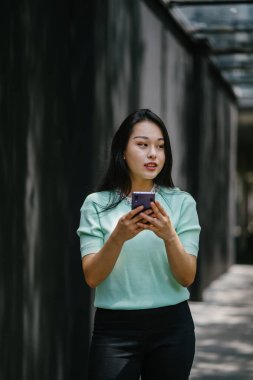 Akıllı telefon tutan genç ve güzel Asyalı bir Çinli kadının portresi.