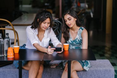 İki yakın arkadaş (kadınlar) gün boyunca bir kafede oturup bir video birlikte Smartphone'da izlerim. Video ve birbirlerinin şirket zevk olarak her ikisi de gülüyorsun.