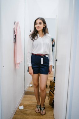 Trying dışarı giyim moda mağaza montaj odasında bir genç, uzun boylu, güzel ve zarif Hint Asyalı kadın portresi.