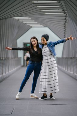 Gündüz vakti köprüde farklı etnik kökenlere sahip iki arkadaş. Biri Malezyalı Müslüman bir kadın, diğeri de Çinli bir Asyalı. İkisi de genç, enerjik ve çekici..