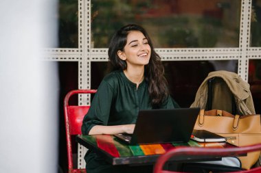 genç üniversite öğrencisi (Hint Asyalı kadın) eğitim ve gün boyunca dizüstü bilgisayar bir masa başında çalışma