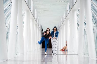 İki farklı arkadaş, iyi aydınlatılmış beyaz fütüristik bir üstgeçit köprüsünden kameraya doğru koşuyorlar. Biri Müslüman bir Orta Doğulu kadın, diğeri de Çinli..