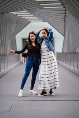 Gündüz vakti köprüde farklı etnik kökenlere sahip iki arkadaş. Biri Malezyalı Müslüman bir kadın, diğeri de Çinli bir Asyalı. İkisi de genç, enerjik ve çekici..