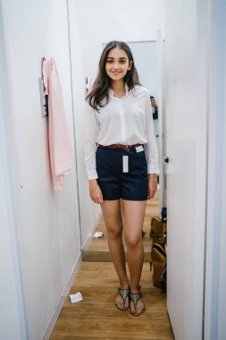 Trying dışarı giyim moda mağaza montaj odasında bir genç, uzun boylu, güzel ve zarif Hint Asyalı kadın portresi.