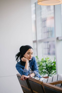 Genç, zarif ve çekici Malezyalı Müslüman kadın gün boyunca elbise ve kot ceket giyiyor..