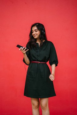 Bir güzel, Genç ve çekici Hint Asyalı kadın bir yeşil elbise ve kırmızı bir arka plan kırmızı kemer Studio portresi