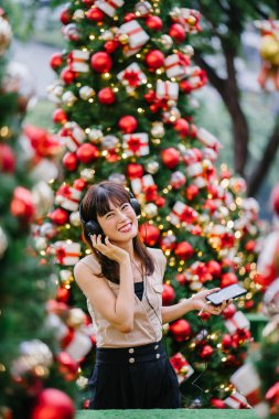 Gün boyunca birkaç süslü Noel ağaçları arasında duran zarif ve çekici bir orta yaşlı kadın portresi