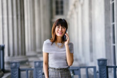 Çekici, kendine güvenen ve başarılı bir Çinli Asyalı kadının portresi. Akıllı telefonuyla konuşuyor. 