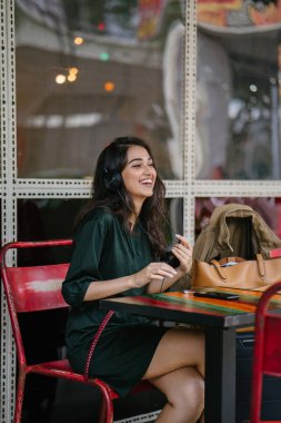 Genç Hintli Asyalı kadın o onun Smartphone-e doğru onun kulaklık streaming müzik hoşlanır