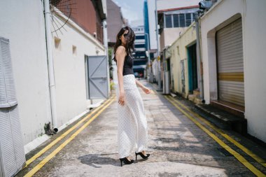 Genç, uzun boylu, ince ve zarif Hint Asyalı kadın rahat bir kıyafet içinde Asya bir sokakta bir sokakta aşağı gün boyunca yürür