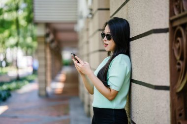 Akıllı telefon tutan genç ve güzel Asyalı bir Çinli kadının portresi.