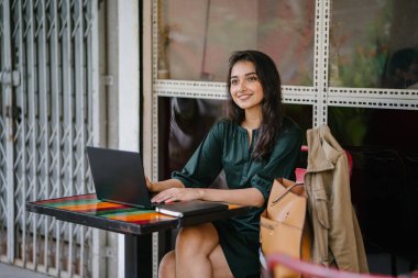 genç üniversite öğrencisi (Hint Asyalı kadın) eğitim ve gün boyunca dizüstü bilgisayar bir masa başında çalışma