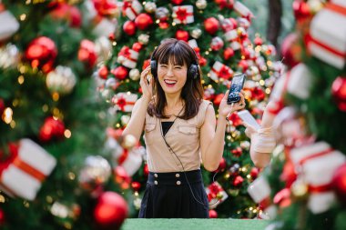 Gün boyunca birkaç süslü Noel ağaçları arasında duran zarif ve çekici bir orta yaşlı kadın portresi