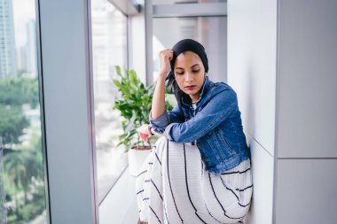 Genç, zarif ve çekici Malezyalı Müslüman kadın gün boyunca elbise ve kot ceket giyiyor..