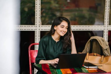 genç üniversite öğrencisi (Hint Asyalı kadın) eğitim ve gün boyunca dizüstü bilgisayar bir masa başında çalışma