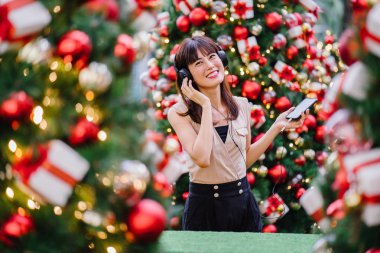 Gün boyunca birkaç süslü Noel ağaçları arasında duran zarif ve çekici bir orta yaşlı kadın portresi