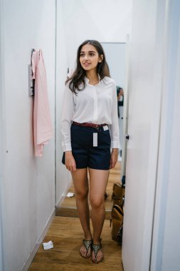 Trying dışarı giyim moda mağaza montaj odasında bir genç, uzun boylu, güzel ve zarif Hint Asyalı kadın portresi.