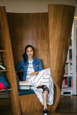 Genç, uzun boylu, zayıf, çekici ve güzel Malezyalı Müslüman kadın kütüphanede oturmuş kitap okuyor. Çalışıyor ve tek başına araştırma yapıyor..