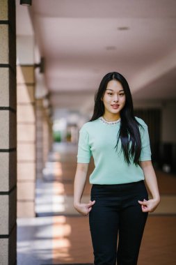 Gündüz vakti genç, seksi ve çekici bir Asyalı kadının portresi. O nane yeşili bir kazak giyiyor.