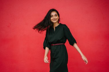 Stüdyo bir güzel, Genç ve çekici Hint Asyalı kadın kırmızı studio çerçevede bir portresi. O zarif bir basit yeşil elbise ve kırmızı kuşak giymiş ve gülüyor.