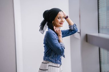 Genç, zarif ve çekici Malezyalı Müslüman kadın gün boyunca elbise ve kot ceket giyiyor..