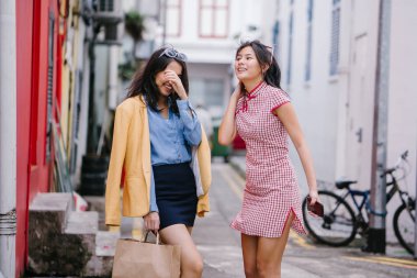 iki yakın arkadaş birlikte bir ara Sokaktan yürürken. Onlar birlikte mutlu bir şekilde yürürken onlar hem trendy retro giyim ve tutuşup giyiyorsun. Çince, diğer Hint biri