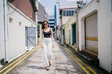 Genç, uzun boylu, ince ve zarif Hint Asyalı kadın rahat bir kıyafet içinde Asya bir sokakta bir sokakta aşağı gün boyunca yürür