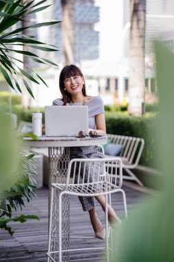 Modern dizüstü bilgisayar kullanarak çekici, kendine güvenen ve başarılı bir Çinli Asyalı kadının portresi