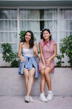 farklı etnik yapı birlikte dışarı asılı iki genç kadın arkadaşlar. Bir Çinli bir kadını bir cheongsam ve diğer bir Hint kadının modaya uygun bir kıyafet olduğunu