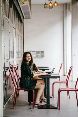 genç üniversite öğrencisi (Hint Asyalı kadın) eğitim ve gün boyunca dizüstü bilgisayar bir masa başında çalışma