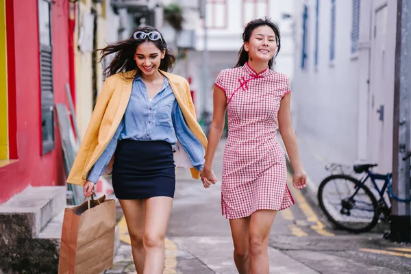 iki yakın arkadaş birlikte bir ara Sokaktan yürürken. Onlar birlikte mutlu bir şekilde yürürken onlar hem trendy retro giyim ve tutuşup giyiyorsun. Çince, diğer Hint biri