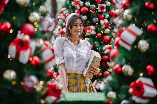 Kırmızı Santa şapka genç ve güzel Çinli Asyalı kadın portresi. O sevilen bir hediye üzerine tutan gibi mutlu gülümsüyor.