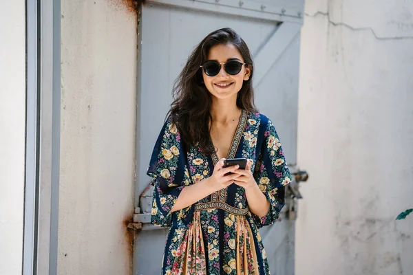 Bir elbise ve onun smartphone ile güneş gözlüğü takan bir genç, çekici ve güzel Hint Asyalı kadın portresi