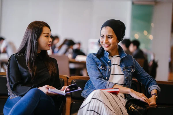 Две Молодые Подруги Сидят Скамейке Читают Книги Обсуждают Одна Мусульманка — стоковое фото