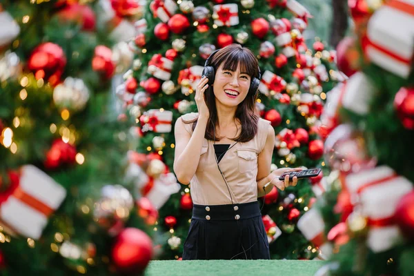 Gün boyunca birkaç süslü Noel ağaçları arasında duran zarif ve çekici bir orta yaşlı kadın portresi