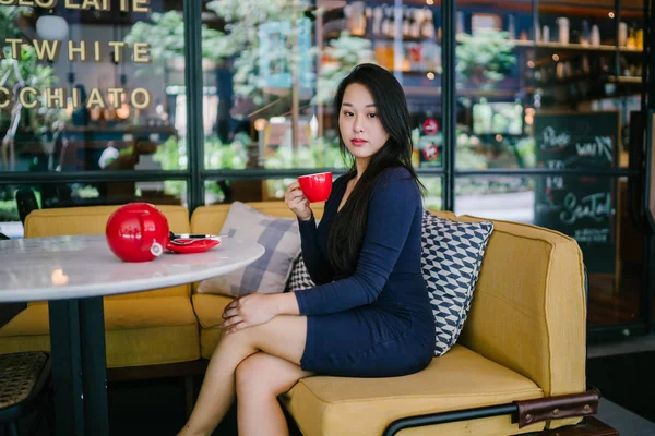 Bir açık havada açık havada oturan ve kırmızı bir çay seti çay sıcak bir fincan zevk genç, çekici, zarif ve güzel Asyalı kadın Portresi. 