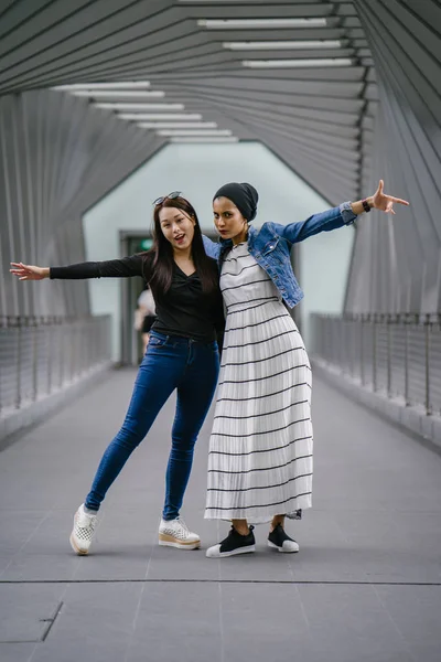 Gündüz vakti köprüde farklı etnik kökenlere sahip iki arkadaş. Biri Malezyalı Müslüman bir kadın, diğeri de Çinli bir Asyalı. İkisi de genç, enerjik ve çekici..