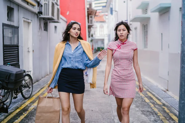 iki yakın arkadaş birlikte bir ara Sokaktan yürürken. Onlar birlikte mutlu bir şekilde yürürken onlar hem trendy retro giyim ve tutuşup giyiyorsun. Çince, diğer Hint biri