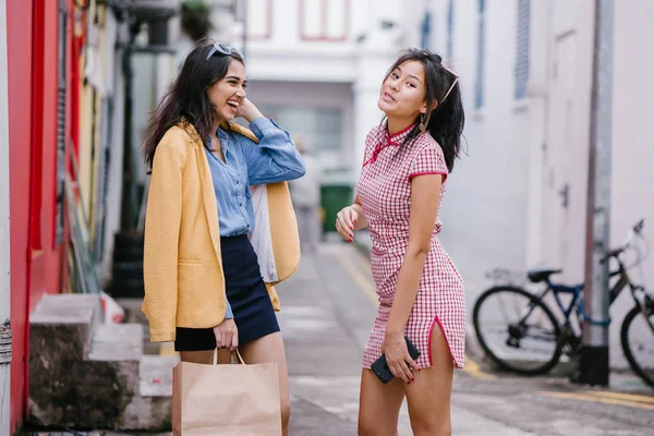 iki yakın arkadaş birlikte bir ara Sokaktan yürürken. Onlar birlikte mutlu bir şekilde yürürken onlar hem trendy retro giyim ve tutuşup giyiyorsun. Çince, diğer Hint biri