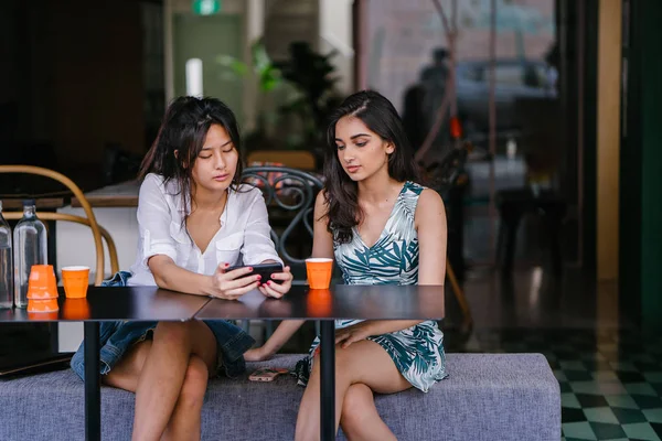 İki yakın arkadaş (kadınlar) gün boyunca bir kafede oturup bir video birlikte Smartphone'da izlerim. Video ve birbirlerinin şirket zevk olarak her ikisi de gülüyorsun.