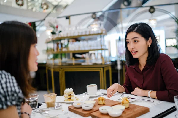 Genç, güzel ve zarif Koreli Asyalı kadın hafta sonu şık bir kafede yakın arkadaşı ile brunch ve çay sahiptir. Onlar kek, çörek ve çay bir yayılma üzerinde animatedly konuşuyorlar. 