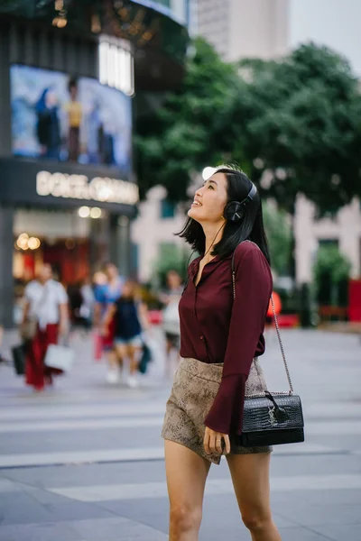 美丽的韩国女人穿着一件优雅的衬衫和短裤跳舞 她走在城市的街道上 戴着耳机 — 图库照片