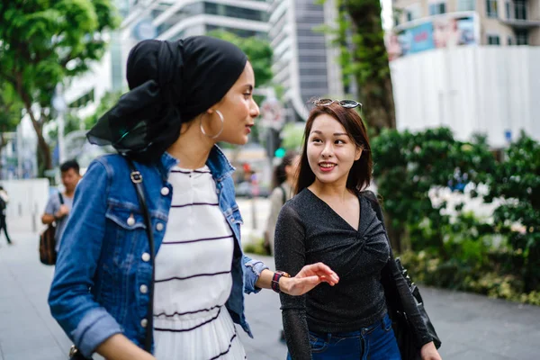 İki arkadaş, Orchard Road, Singapur, Asya 'da aydınlık bir yaz gününde mutlu bir şekilde yürüyüp konuşurlar. Biri Müslüman Malezyalı, diğeri Çinli bir kadın.. 