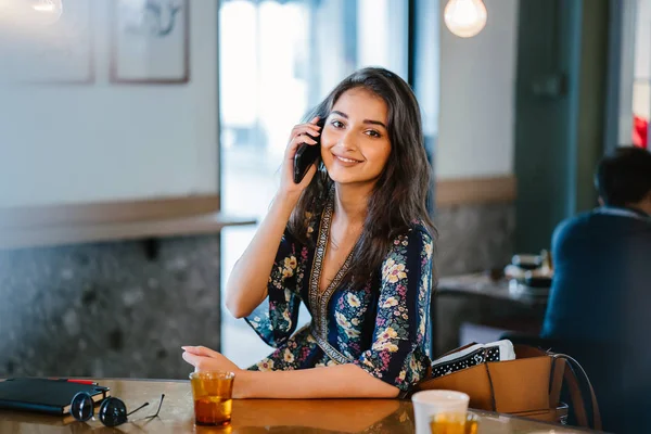 Bir kafede onu smartphone o görüşmeler olarak gündüzleri çatık bir genç ve çekici Hint Asyalı kadın portresi