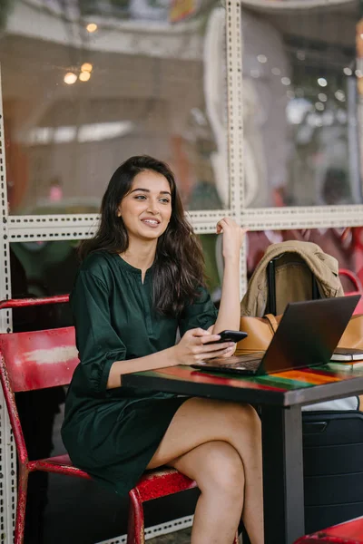 Genç Singpaorean Kızılderili kadın eğitim ya da bir kafede gün boyunca onu laptop çalışan bir mola alır gibi onun smartphone kontrol