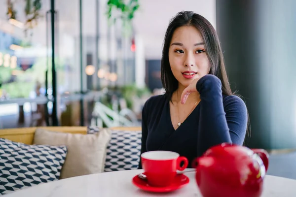 Bir açık havada açık havada oturan ve kırmızı bir çay seti çay sıcak bir fincan zevk genç, çekici, zarif ve güzel Asyalı kadın Portresi. 