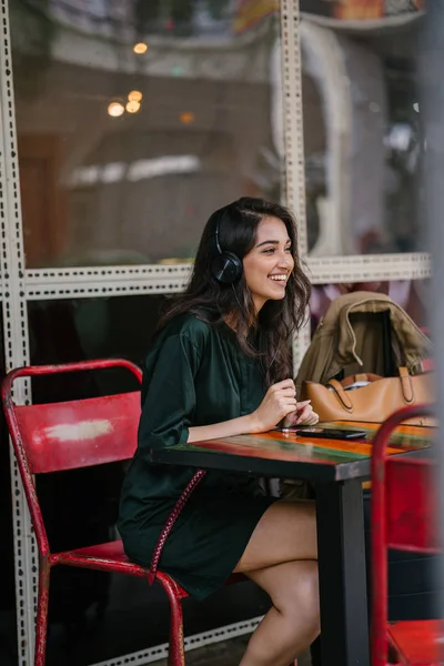 Genç Hintli Asyalı kadın o onun Smartphone-e doğru onun kulaklık streaming müzik hoşlanır