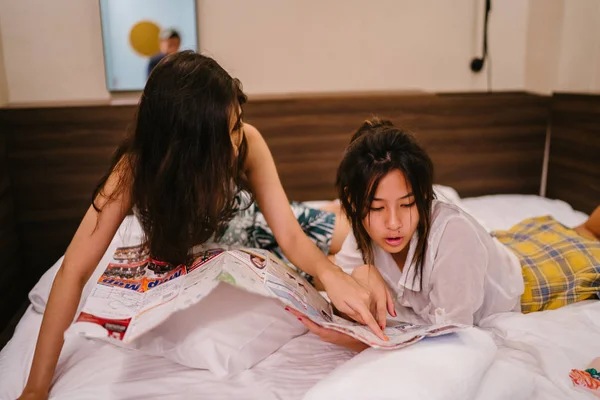 İki genç Asyalı arkadaş bir pansiyonda bir yatakta oturuyor. İkisi de Asyalı ve birlikte seyahat ediyorlar. Biri Hintli, diğeri Çinli. İkisi de gündelik giysiler içinde ve odalarında dinleniyorlar..