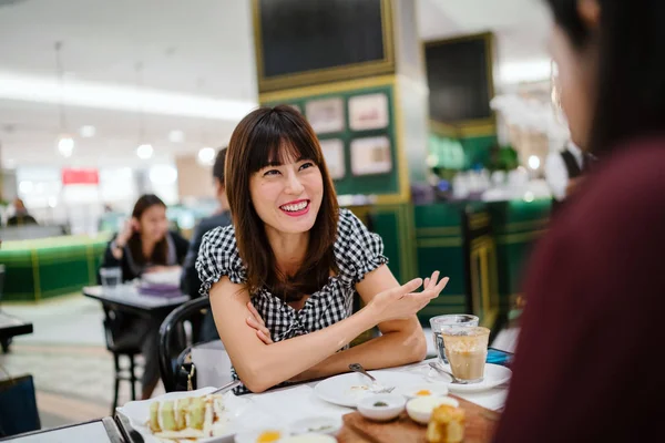 Bir Çinli Asyalı bayan bir restoranda iyi bir arkadaş ile yüksek çay sahiptir. O güzel, zarif ve o bir hafta sonu kek ve çay üzerinde arkadaşı ile animatedly konuşuyor gibi gülümsüyor. 